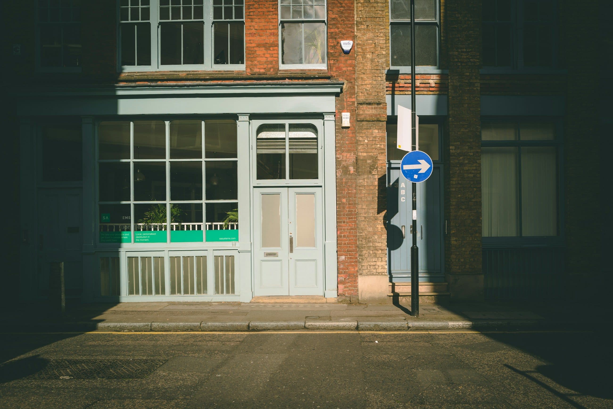 An empty Victorian shopfront with a pale green frame on Tabernacle Street in Shoreditch, in early morning light
