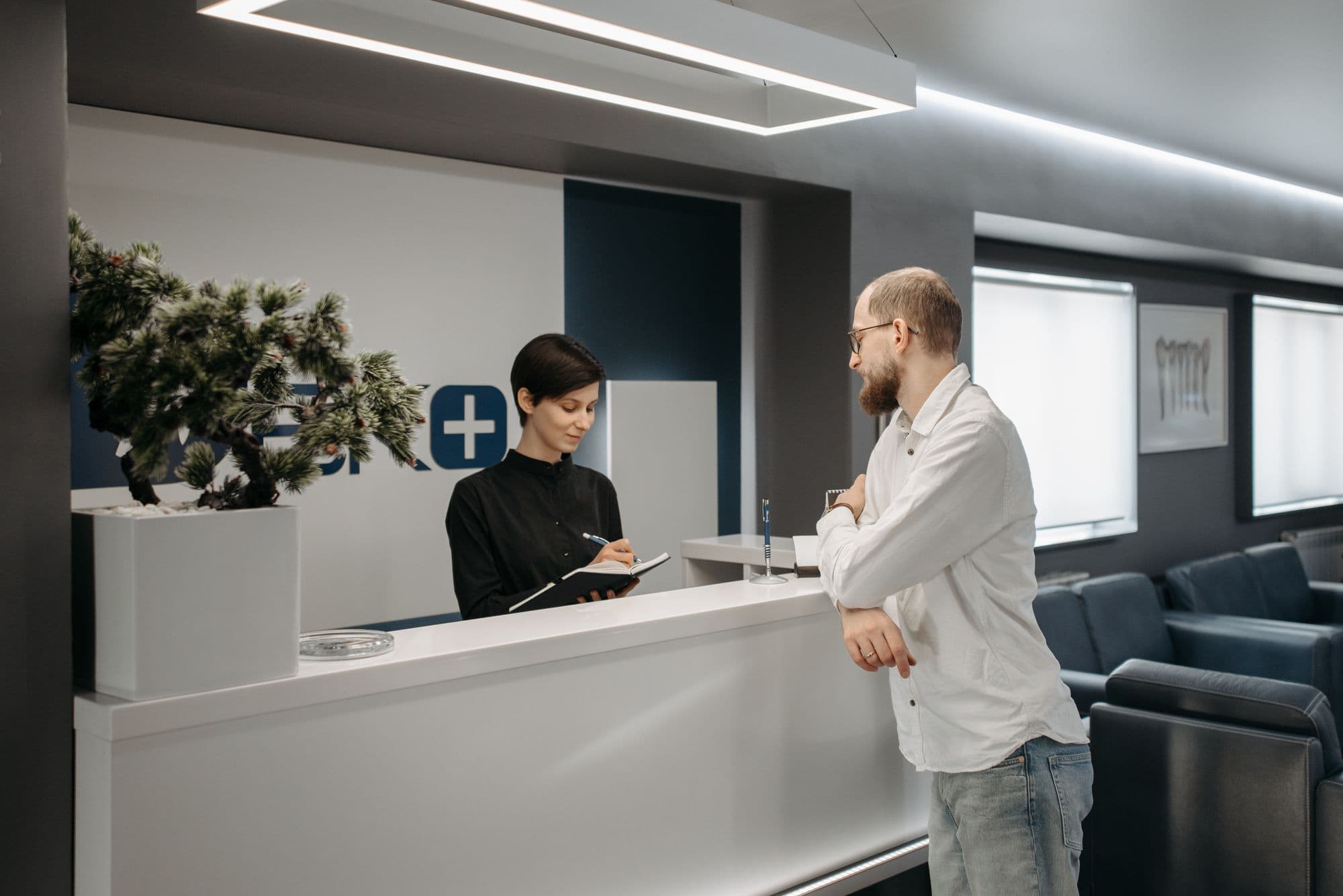 A patient being checked in at the reception of a modern multi-site private clinic