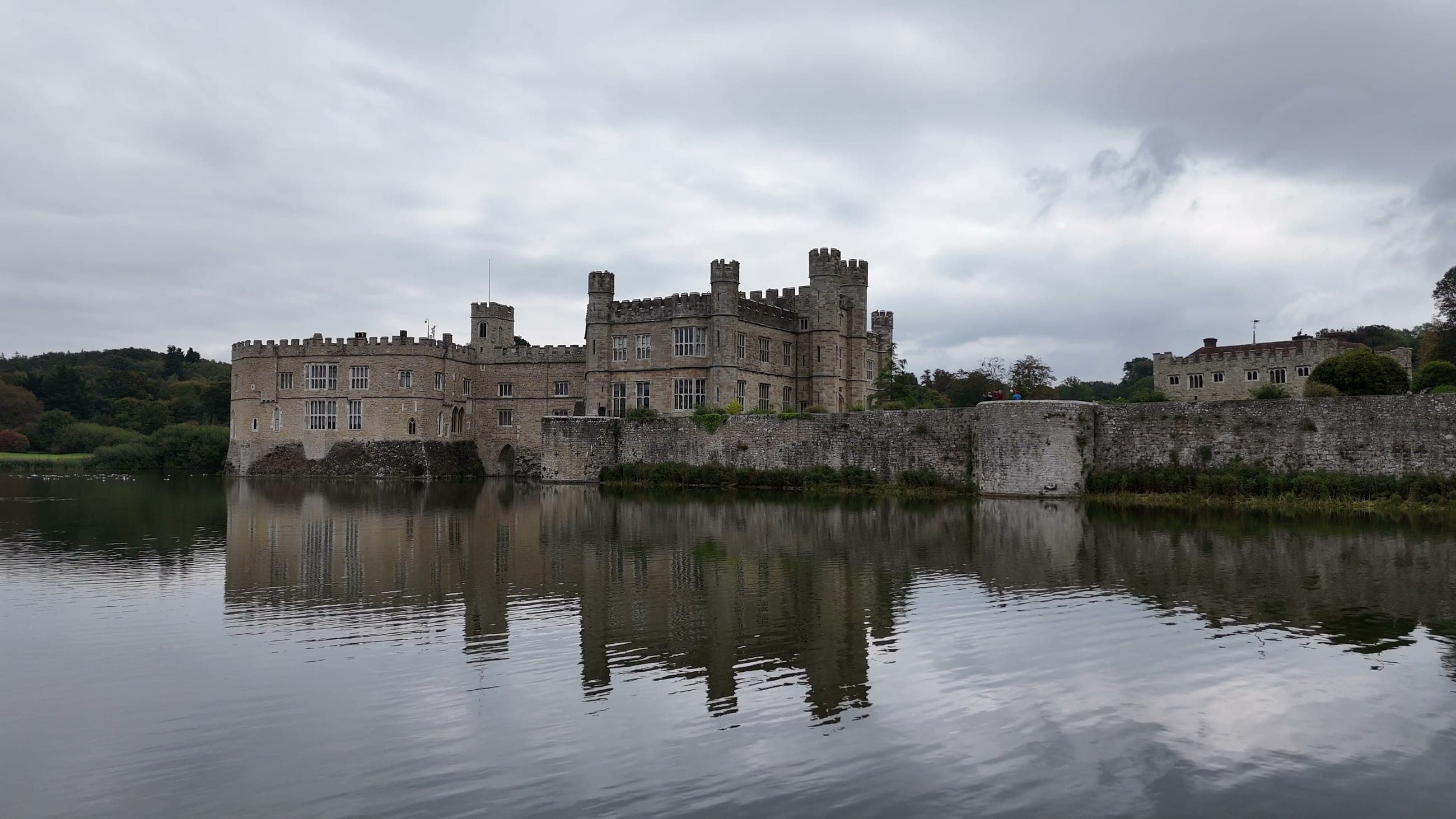 Leeds Castle in Kent seen across its moat, with the castle walls reflected in still water
