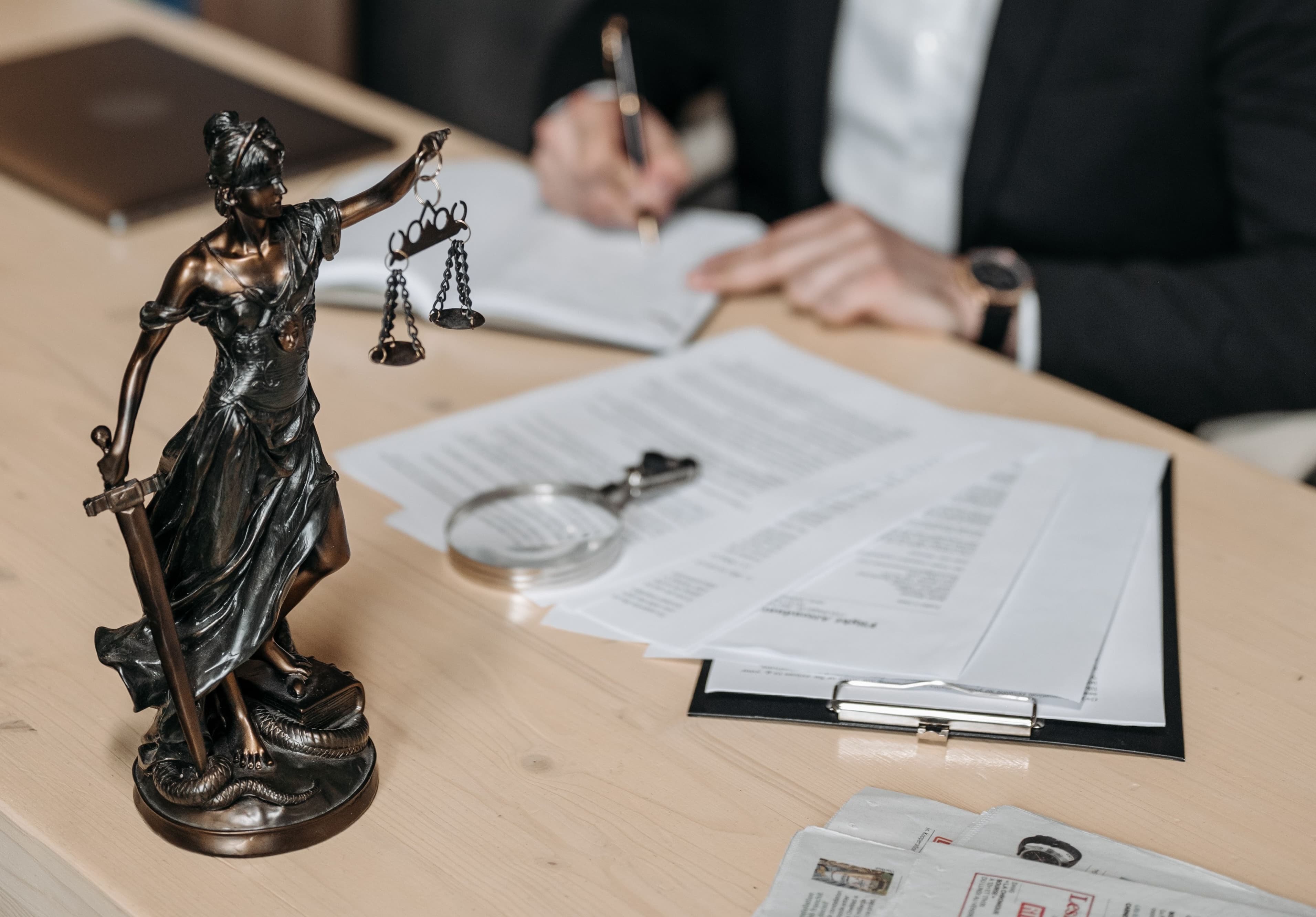 Solicitor's office with a partner reviewing a case file at a desk, law reports on the shelves behind and a laptop showing a firm's website