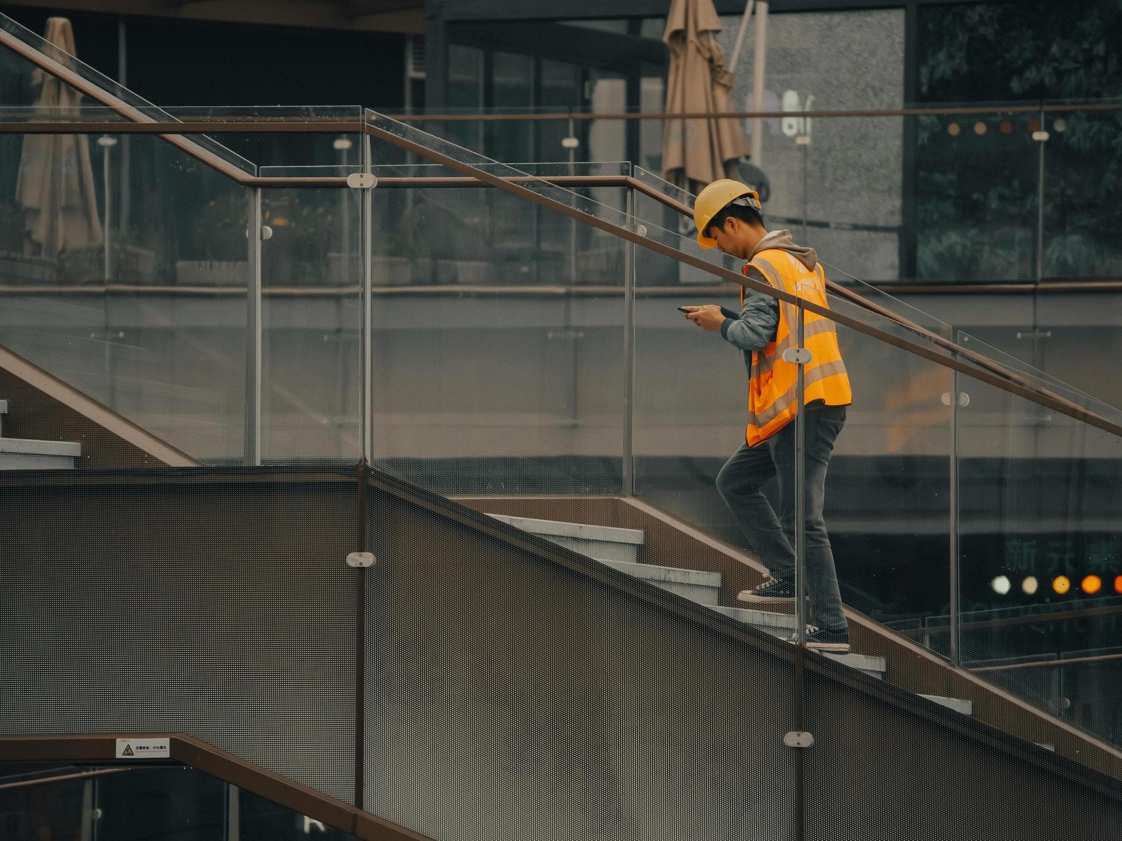 Tradesperson in workwear reviewing a website on a phone at a job site, ladder and tools in the background