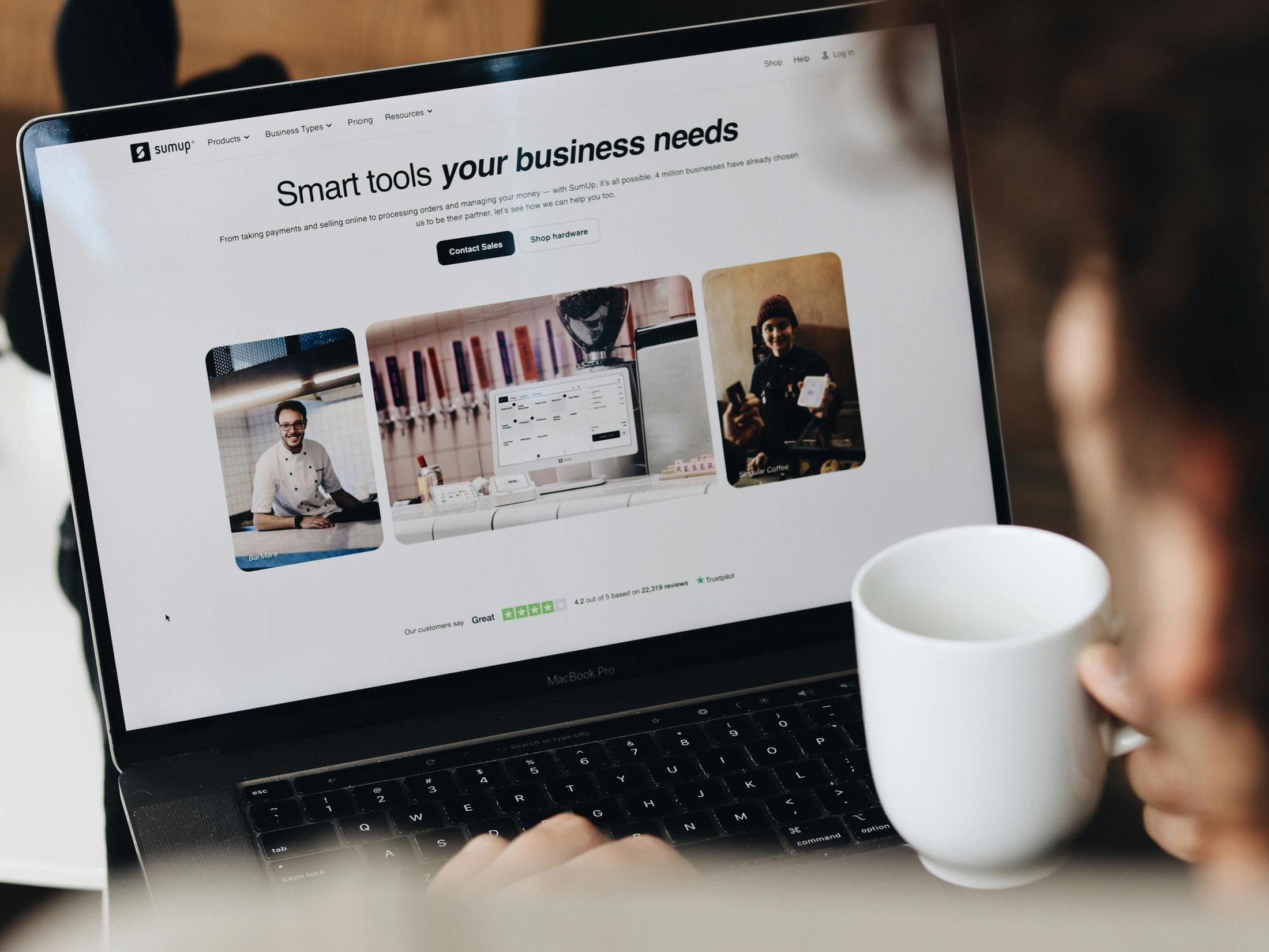 A man drinking coffee and browsing websites on his laptop
