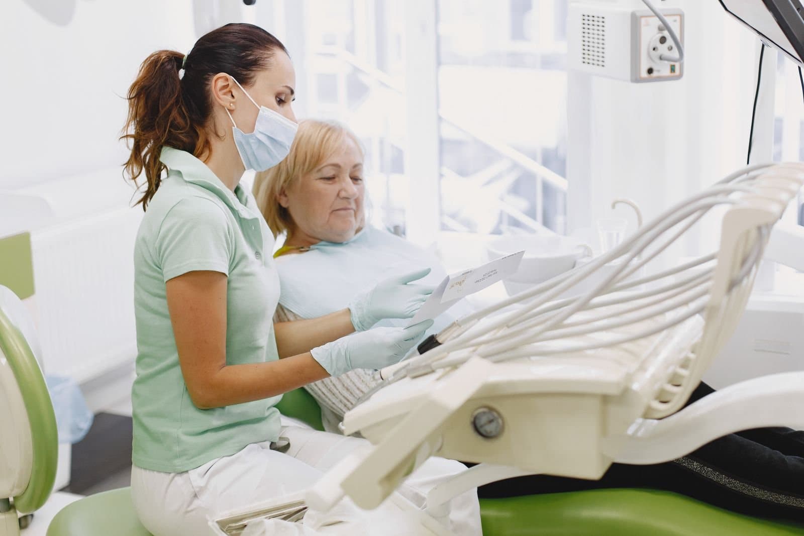 A dentist talking a patient through her treatment in the chair
