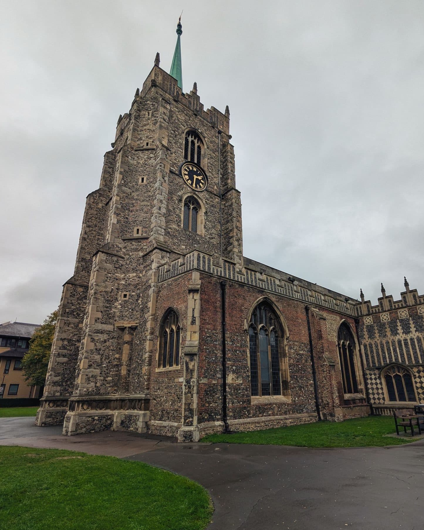 The flint tower and green spire of Chelmsford Cathedral under a grey sky