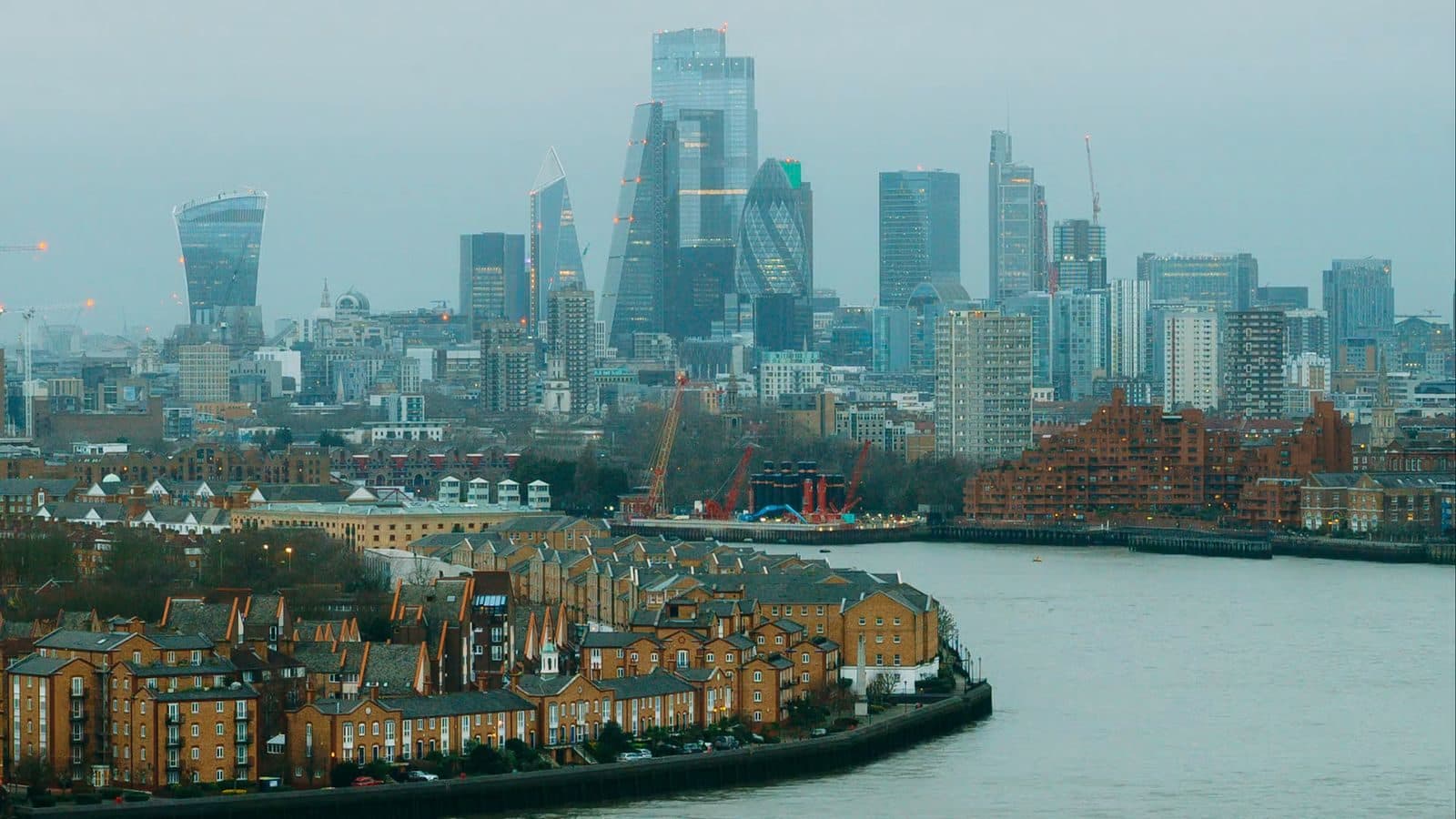 The towers of the City of London above a bend of the Thames at dusk, seen from high up