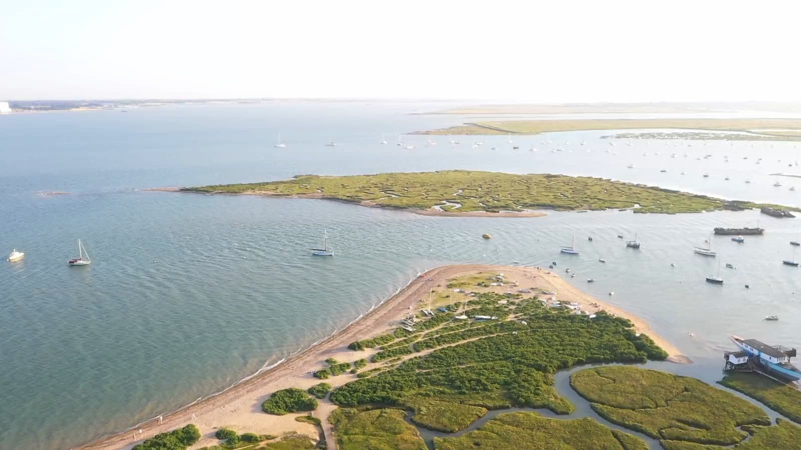 The saltmarsh, creeks and moored boats of Mersea Island in Essex, seen from the air in evening light
