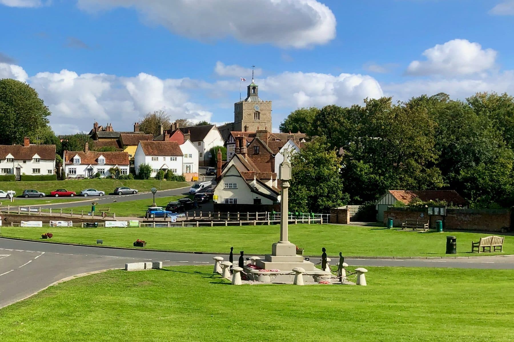 The village green at Finchingfield in Essex, with the war memorial, cottages and church tower under a bright sky