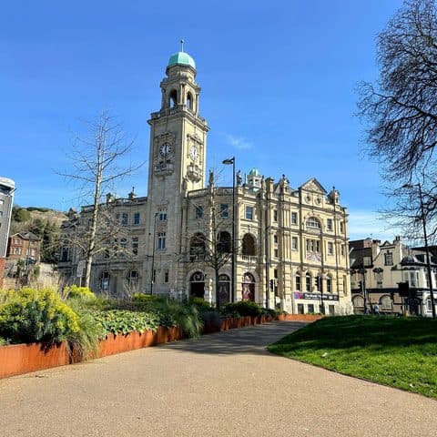 The clock tower of the Brook Theatre above the gardens at Chatham Waterfront in Medway